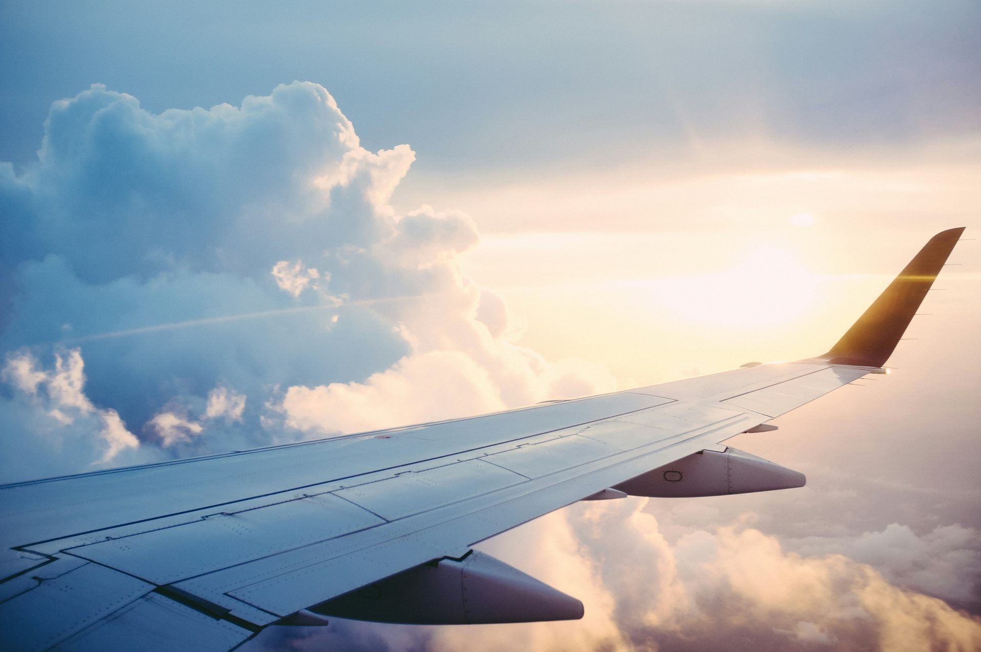 Airplane wing above the clouds at sunrise